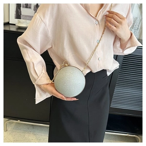 Silver sphere clutch bag with gold chain strap shown on model for size perspective