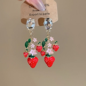 Close-up of strawberry earrings with red enamel and large oval sparkling clear gemstones