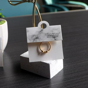 Detail of a gold ring on grey marble jewelry display card with inspirational quote