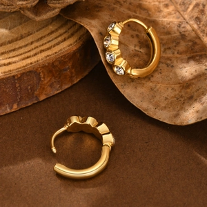 Close-up of gold star earrings with round cubic zirconia on natural wood background
