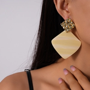 Detail of model wearing gold hammered metal and pale yellow marble acrylic earrings
