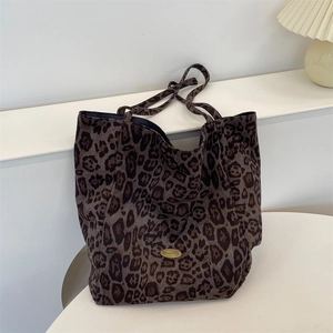 Close-up of leopard print tote bag with golden logo plaque on white decorative stairs