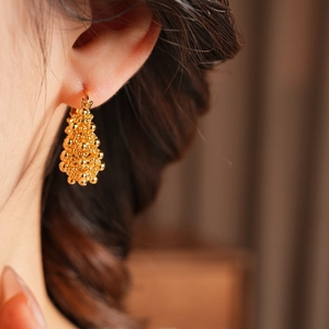 Gros plan de boucles d'oreilles grappes perlées plaquées or 18 carats sur un modèle