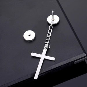Detail view of silver cross pendant earring with circle stud and link chain on black surface