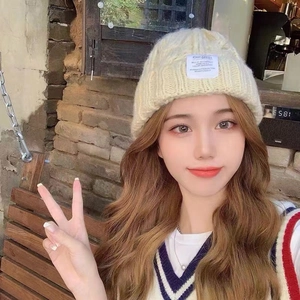 Beige chunky knit beanie with Jiang Fashion patch on model in outdoor setting
