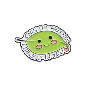 Leaf enamel brooch with 'I BELEAF IN YOU' quote on a white background