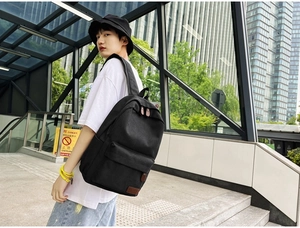 Detail of black canvas backpack showing durable fabric and vintage leather patch logo