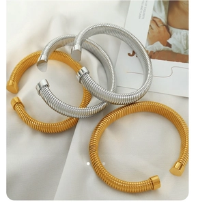 Detailed view of gold and silver coiled spring bracelets on elegant white satin fabric