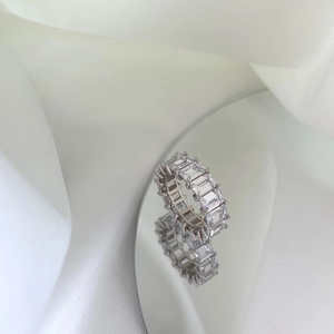 Macro view of silver S925 ring with emerald-cut cubic zirconia on reflective surface