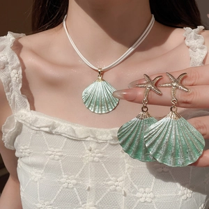 Detail of mint green shell pendant necklace and starfish earrings on model