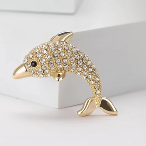 Elegant gold dolphin brooch with sparkling rhinestones on a white minimalist background