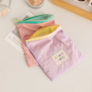 Close-up of macaroon-colored nylon cosmetic pouch with contrast zipper and embroidery