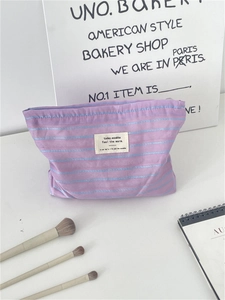 Detail of a purple striped canvas cosmetic bag with text label and soft cotton texture