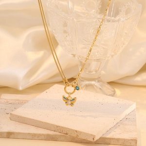 Golden butterfly necklace with blue gemstone on beige stone and satin background