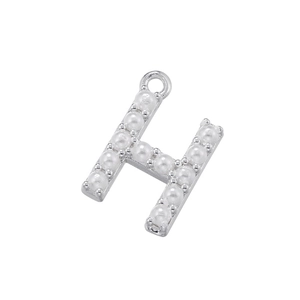 Macro shot of silver letter H pendant inlaid with small white pearls for jewelry making