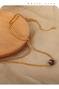 Macro shot of double-layered gold chain necklace with square agate pendant on wood