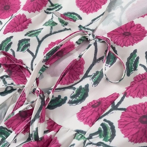 Détail de la chemise blanche à imprimé floral rose avec un nœud élégant au décolleté