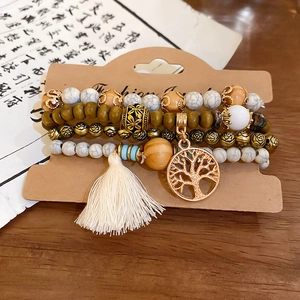 Detail of bohemian layered beads with a rose-patterned bead and Tree of Life charm