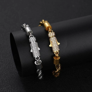 Gold and silver twist chain bracelets with iced-out pendants on a black display stand