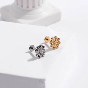 Macro detail of snowflake labret studs in gold and silver finish on white stone