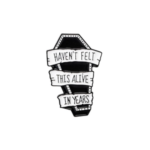 Detailed view of coffin enamel pin with text Haven't felt this alive in years