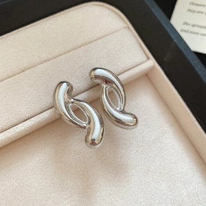 Close-up of elegant silver twisted knot stud earrings on a beige velvet jewelry display