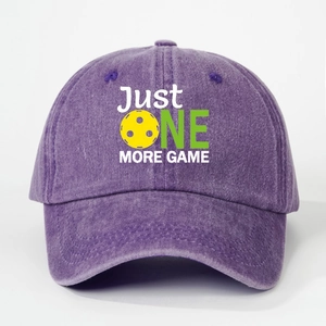 Detail showing embroidered Just One More Game text and pickleball icon on purple cap