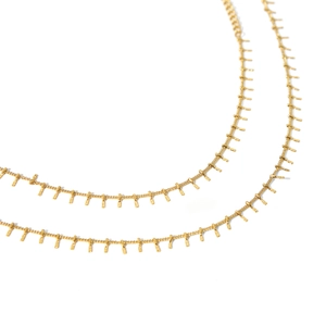 Detail of 18K gold-plated tassel necklace with small rectangular metal bars on white background