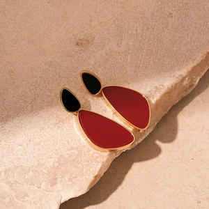 Detail view of vintage geometric wine red and black heart-shaped earrings on stone surface