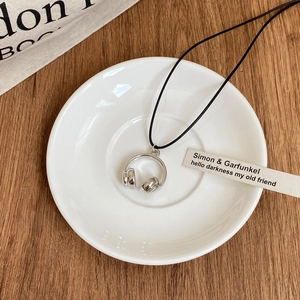 Gros plan d'un collier avec pendentif casque créatif sur une assiette en céramique blanche