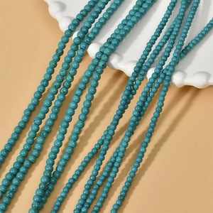 Strands of 3-4mm turquoise round beads displayed on a white wavy plate for DIY jewelry making