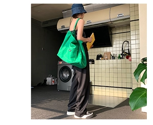 Lifestyle shot of a spacious green canvas tote bag featuring front pocket and strap