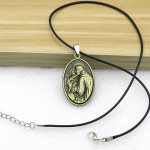 Detail view of Saint Anthony bronze pendant with embossed relief on black wax cord necklace