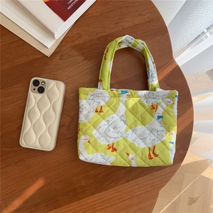 Macro detail of yellow quilted phone bag with white duck pattern on wooden table