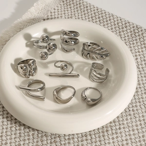 Minimalist silver geometric stainless steel rings displayed on white ceramic tray