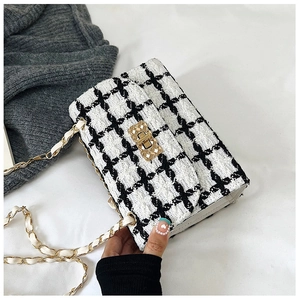 Detail of tweed crossbody bag with golden chain strap and metallic lock closure