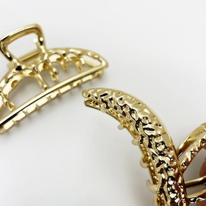 Macro view of gold metal hair claw clip showing hinge detail and textured teeth