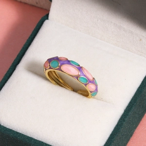 Détail de la bague en émail doré avec points colorés dans un écrin vert