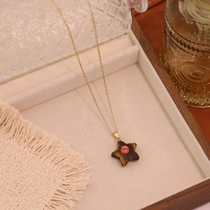 Detailed shot of star stone pendant necklace with pink bead on a soft jewelry display