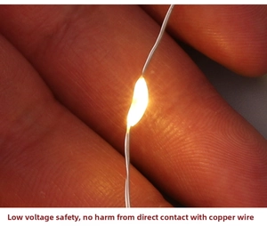 Macro view of warm yellow LED copper wire string lights showing safe low voltage touch