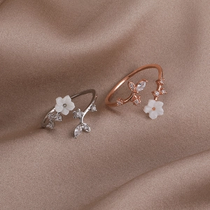 Detail of silver and rose gold flower rings with pearls on soft silk fabric