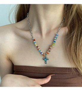 Detail of colorful stone beads and a blue cross pendant on a stylish necklace