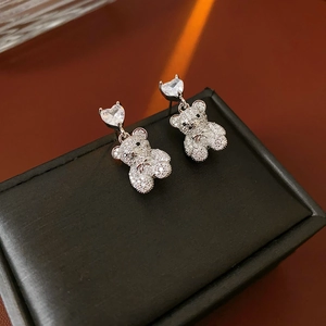 Détail des boucles d'oreilles ours en zircon avec cœur sur un étui en cuir noir