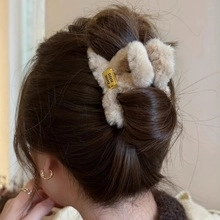 Detail of plush cream hair claw with yellow Good Thing label on a loose hair bun