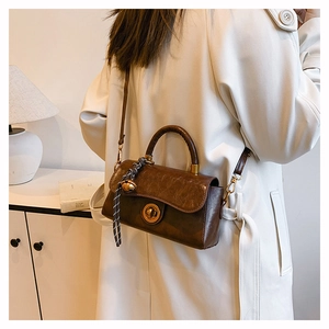 Detail of vintage brown leather handbag with striped silk scarf handle and gold twist lock