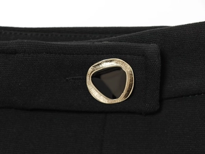 Detail van de zwarte geweven stof met een goudkleurige en zwarte driehoekige metalen knoop