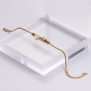 Macro shot of gold-plated snake chain bracelet with heart charm and sparkling rhinestones