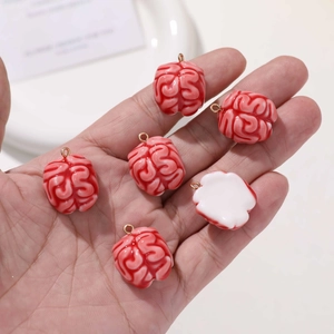 Macro shot of six pink resin brain pendants on a palm showing DIY jewelry size and detail