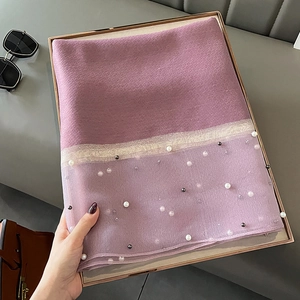 Detailed shot of purple silk scarf with elegant pearl embellishments and metallic trim