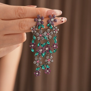 Détail de boucles d'oreilles vintage fleurs à pompons avec strass vert émeraude